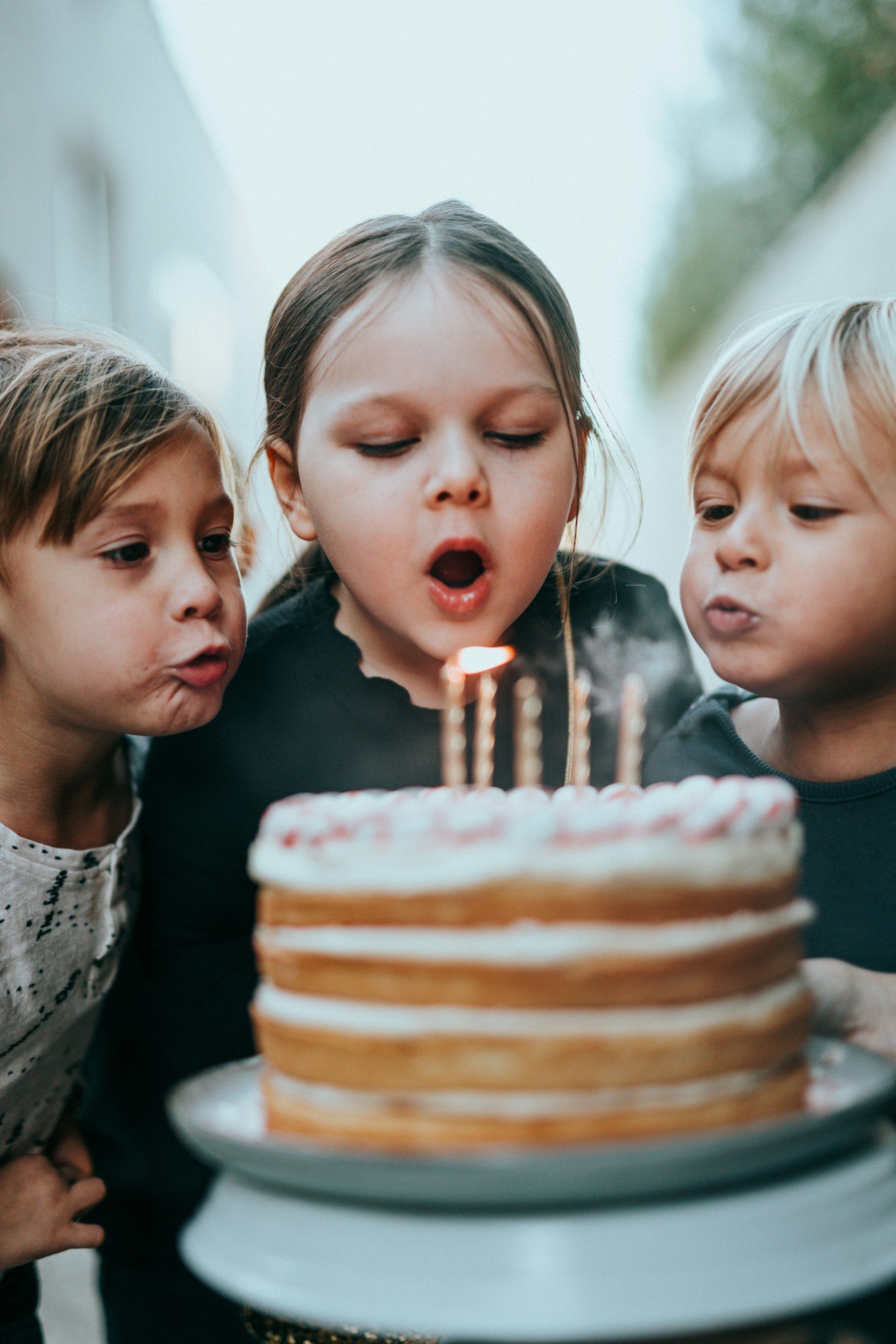Trois enfants soufflent les bougies d’un gâteau